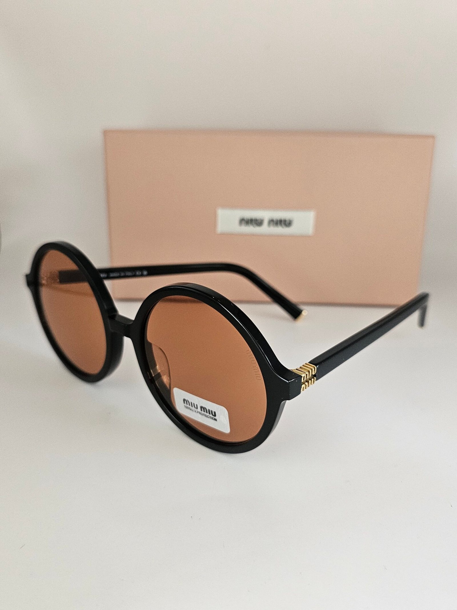 Miu Miu — Gafas redondas negras con lentes ámbar