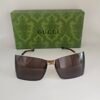 Gucci — Gafas envolventes doradas con lentes marrones