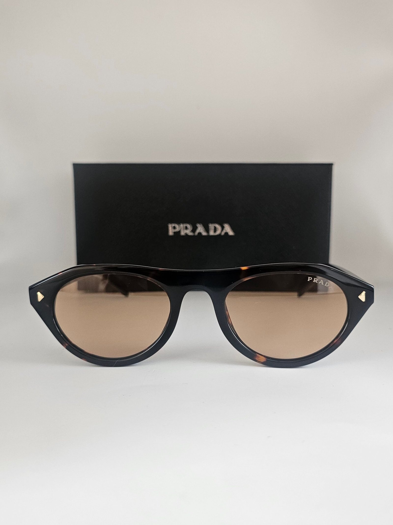 Prada — Gafas negras con lentes beige