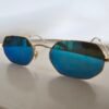 Ray-Ban — Gafas geométricas doradas con lentes azules