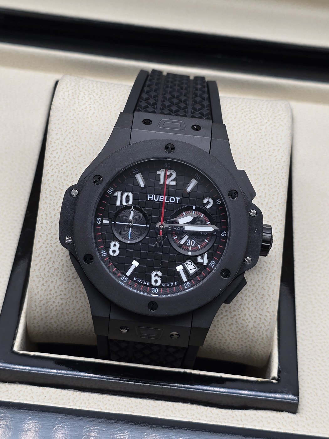 Hublot — esfera negra con apertura y caja gris oscura
