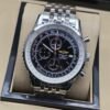 Breitling — esfera negra con detalles rojos y brazalete plateado