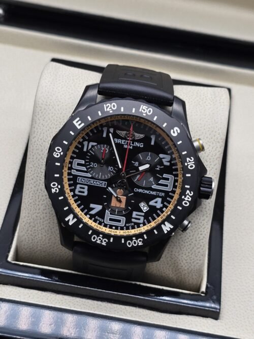 Breitling — esfera negra con detalles dorados y correa negra