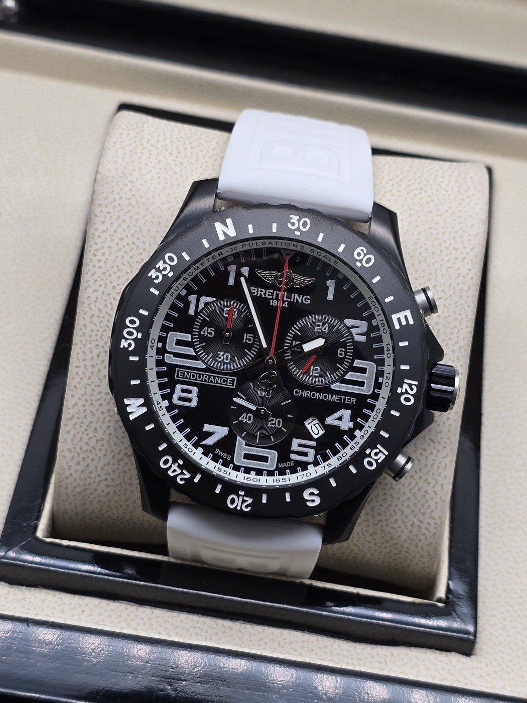 Breitling — esfera negra deportiva y correa blanca
