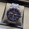 Tissot — esfera negra con detalles naranjas y brazalete plateado