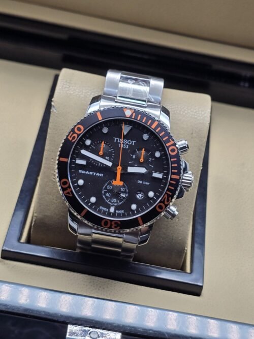 Tissot — esfera negra con detalles naranjas y brazalete plateado