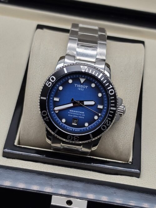 Tissot — esfera azul con bisel negro y brazalete plateado