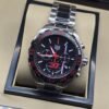 TAG Heuer — esfera negra con detalles rojos y brazalete plateado