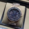 TAG Heuer — esfera oscura con detalles azules y brazalete rosado