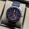 TAG Heuer — esfera negra con detalles rojos y correa perforada negra