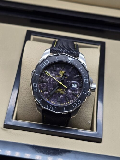TAG Heuer — esfera oscura con detalles amarillos y correa negra