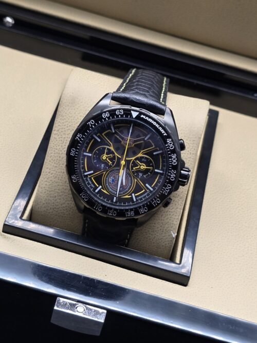 TAG Heuer — esfera oscura con detalles amarillos y correa negra