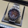 TAG Heuer — esfera oscura con detalles naranjas y brazalete plateado