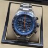 TAG Heuer — esfera azul con detalles naranjas y brazalete plateado