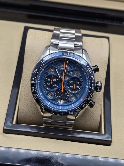 TAG Heuer — esfera azul con detalles naranjas y brazalete plateado