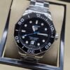 TAG Heuer — esfera negra con aguja azul y brazalete plateado