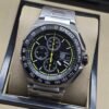 TAG Heuer — esfera negra con detalles amarillos y brazalete plateado