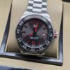 TAG Heuer — esfera gris con detalles rojos y brazalete plateado