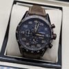 TAG Heuer — esfera oscura con números dorados y correa marrón