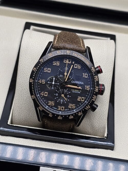 TAG Heuer — esfera oscura con números dorados y correa marrón