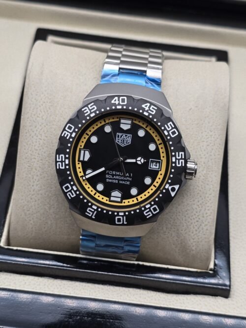 TAG Heuer — esfera negra con aro amarillo y brazalete plateado