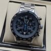 TAG Heuer — esfera negra con detalles azules y brazalete plateado