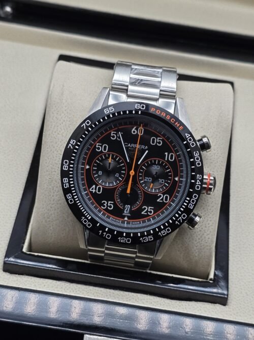 TAG Heuer — esfera negra con detalles naranjas y brazalete plateado