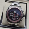 TAG Heuer — esfera negra con detalles rojos y brazalete plateado