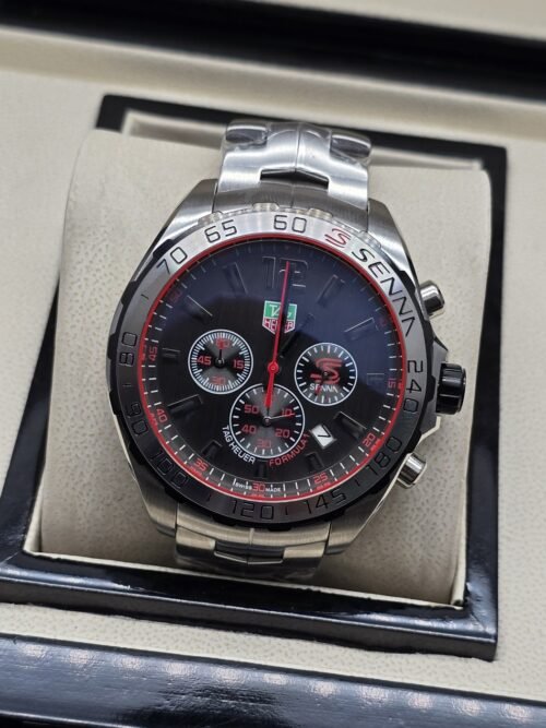 TAG Heuer — esfera negra con detalles rojos y brazalete plateado