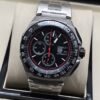 TAG Heuer — esfera negra con detalles rojos y brazalete plateado