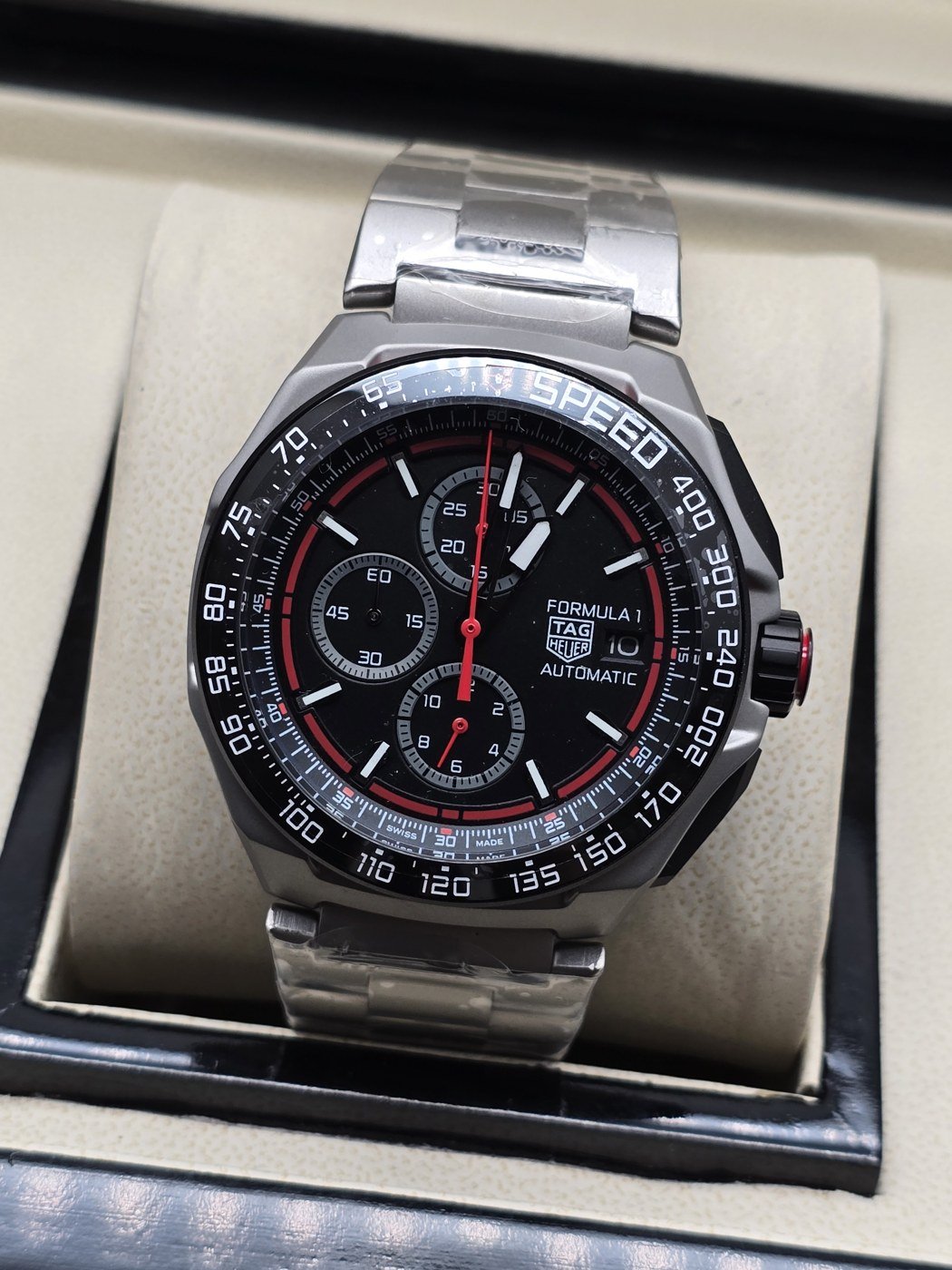 TAG Heuer — esfera negra con detalles rojos y brazalete plateado