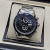 TAG Heuer — esfera oscura con dos subesferas verticales y brazalete plateado