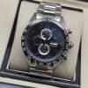 TAG Heuer — esfera oscura con subesferas verticales y brazalete plateado