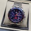 TAG Heuer — esfera azul con detalles rojos y brazalete plateado