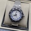 TAG Heuer — esfera blanca con aro azul y brazalete plateado