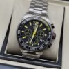 TAG Heuer — esfera negra con números amarillos y brazalete plateado