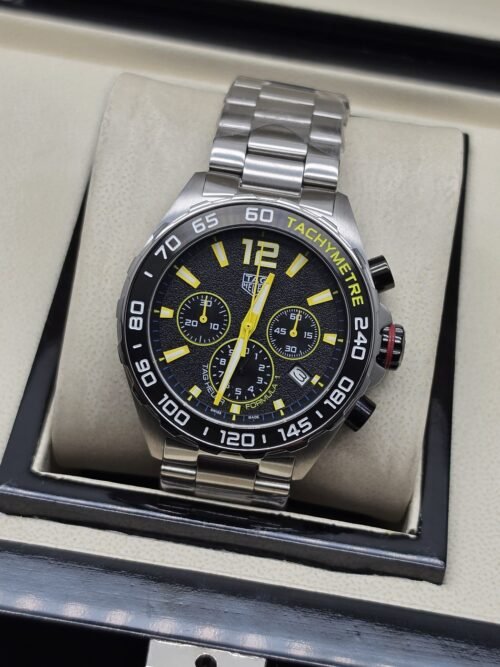 TAG Heuer — esfera negra con números amarillos y brazalete plateado