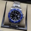 Rolex — esfera negra con bisel azul y brazalete plateado