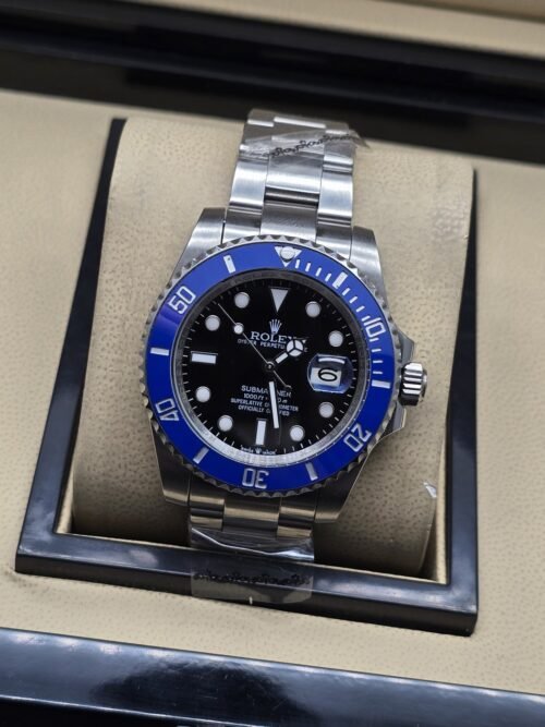 Rolex — esfera negra con bisel azul y brazalete plateado