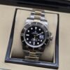 Rolex — esfera negra con acentos dorados y brazalete bicolor