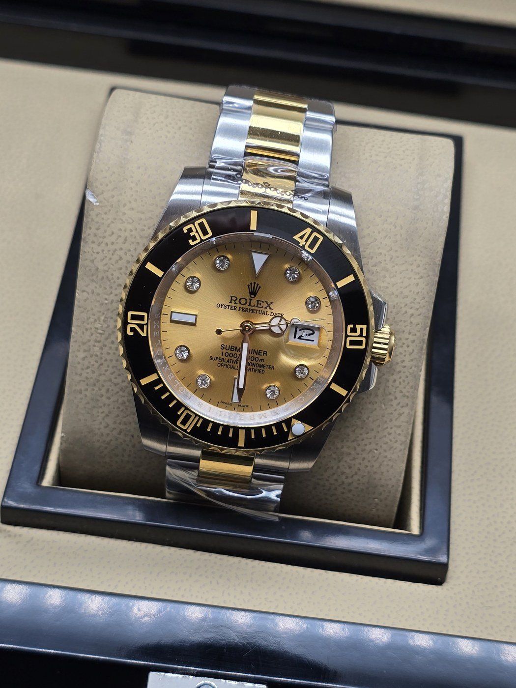 Rolex — esfera dorada con bisel negro y brazalete bicolor
