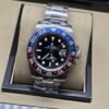 Rolex — esfera negra con bisel rojo y azul, brazalete plateado