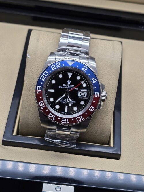Rolex — esfera negra con bisel rojo y azul, brazalete plateado