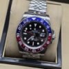 Rolex — esfera oscura con bisel rojo y azul, brazalete plateado