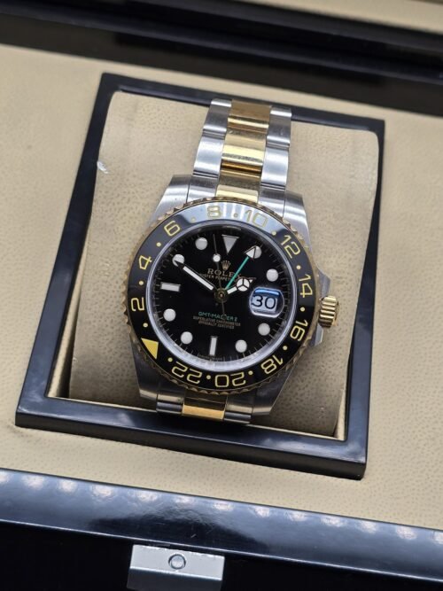 Rolex — esfera negra con numeración dorada en bisel y brazalete bicolor
