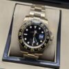 Rolex — esfera negra con bisel numerado y brazalete dorado