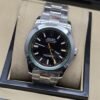 Rolex — esfera negra con aguja naranja, aro verde y brazalete plateado