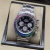 Rolex — esfera negra con detalles brillantes, bisel multicolor y brazalete plateado
