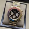 Rolex — esfera negra con subesferas doradas, bisel multicolor y brazalete dorado