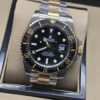 Rolex — esfera negra con numeración dorada y brazalete bicolor